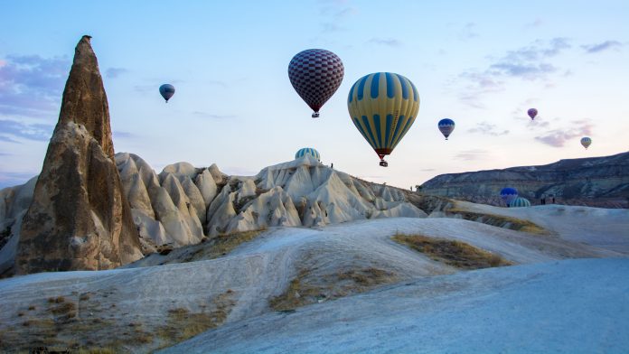 Hot air balloons above Cappadocia’s eroded rock formations at sunrise