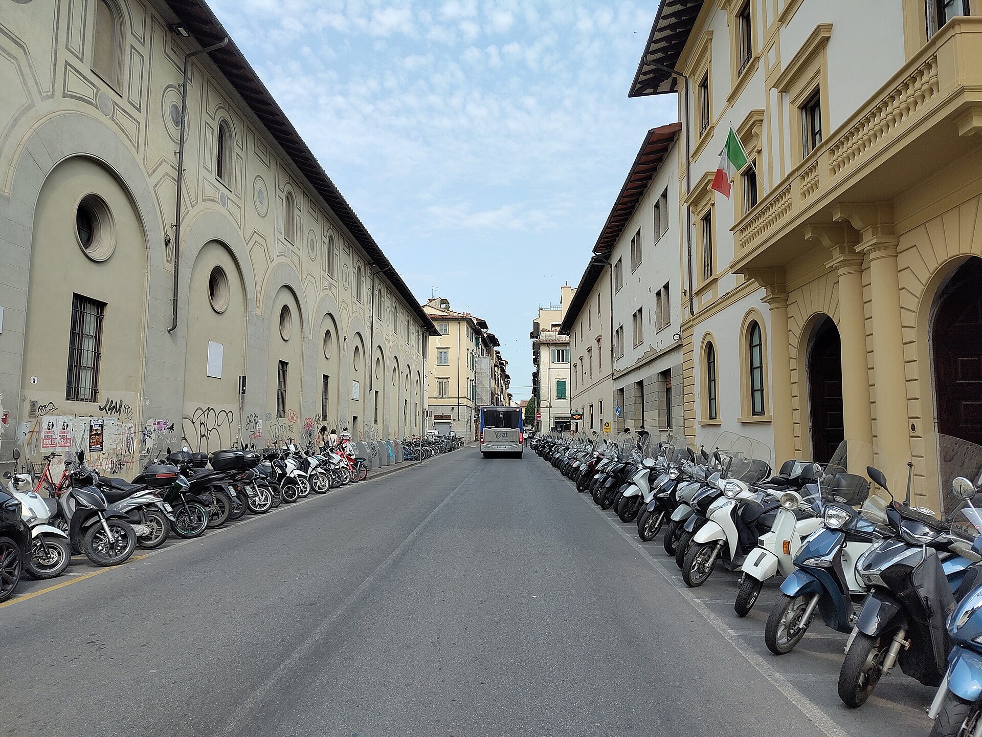 A street in Florence lined with buildings and parked scooters.