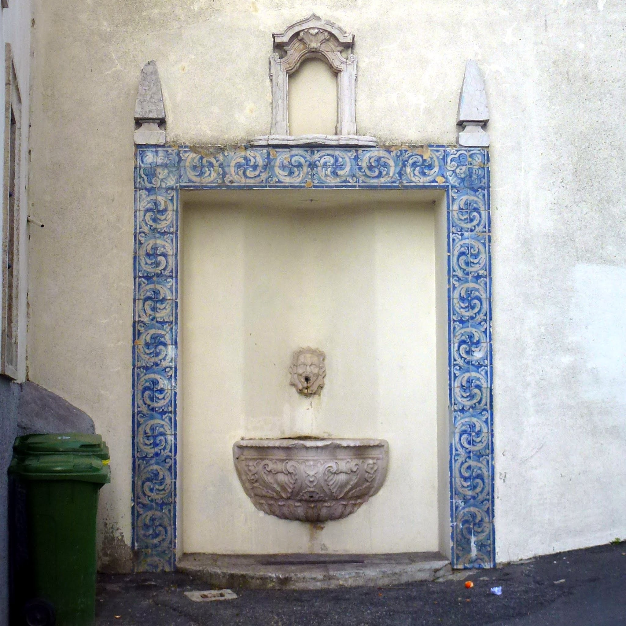 A tiled fountain set into an Alfama wall.