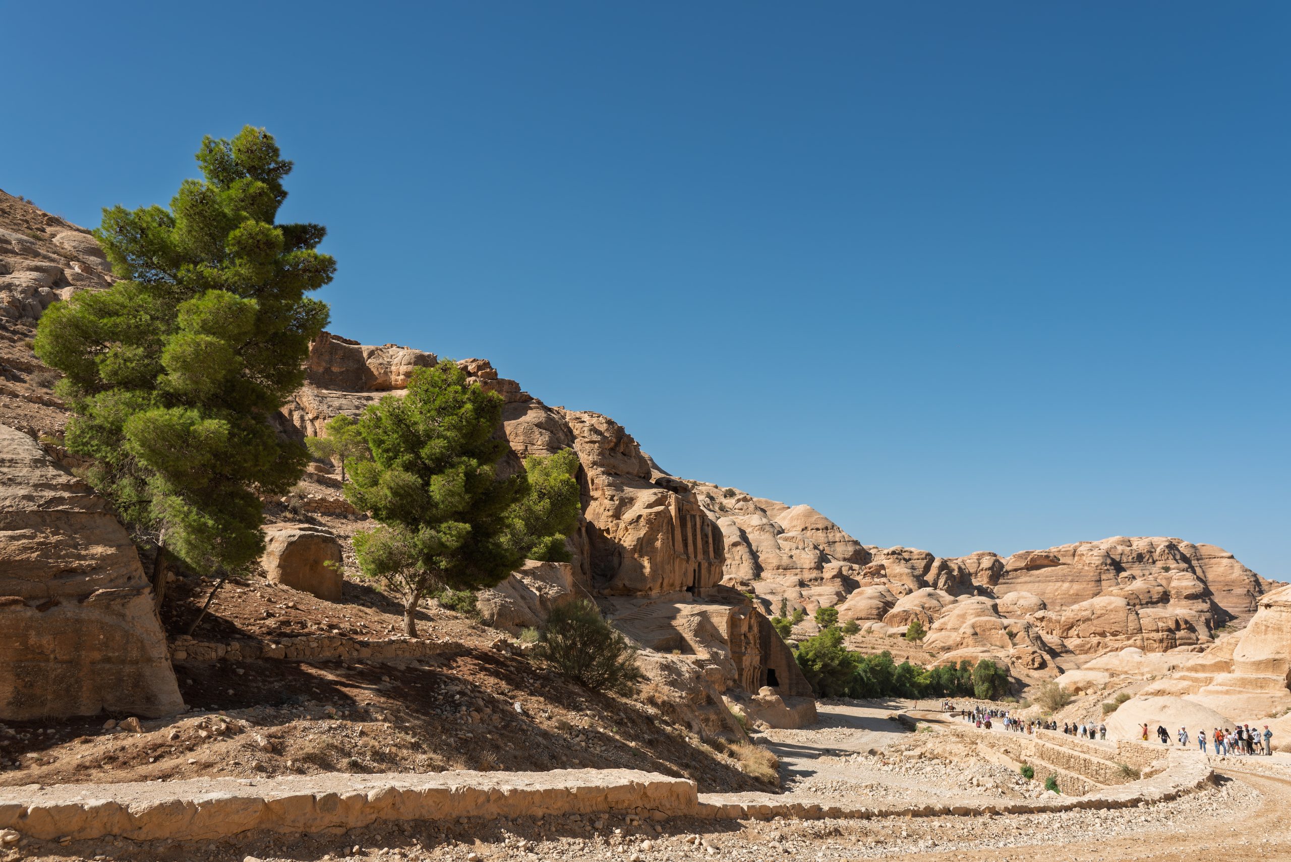 Visitors walking through the rocky archaeological landscape at Petra